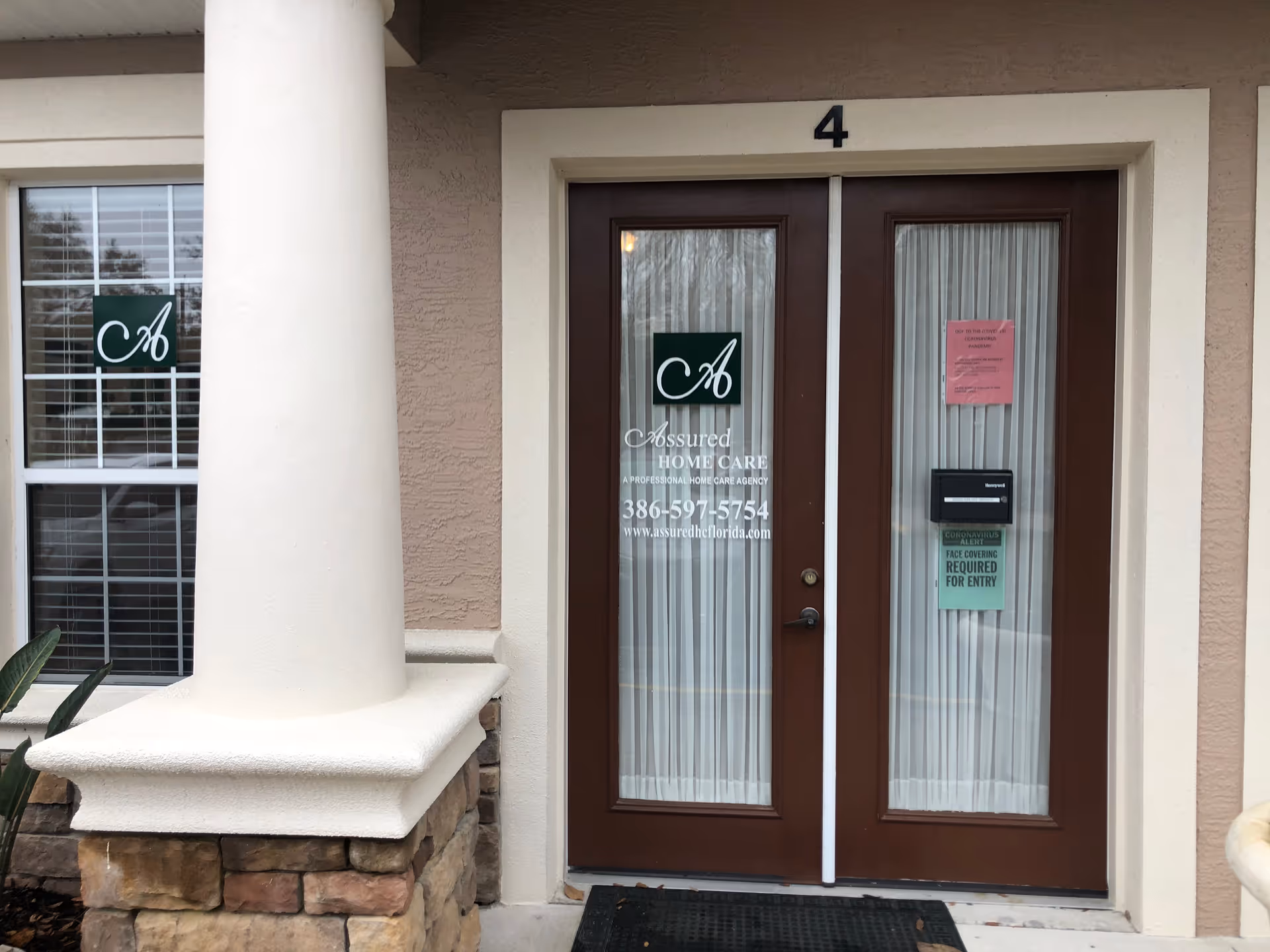 Exterior entrance to Assured Home Care facility with double doors and a column