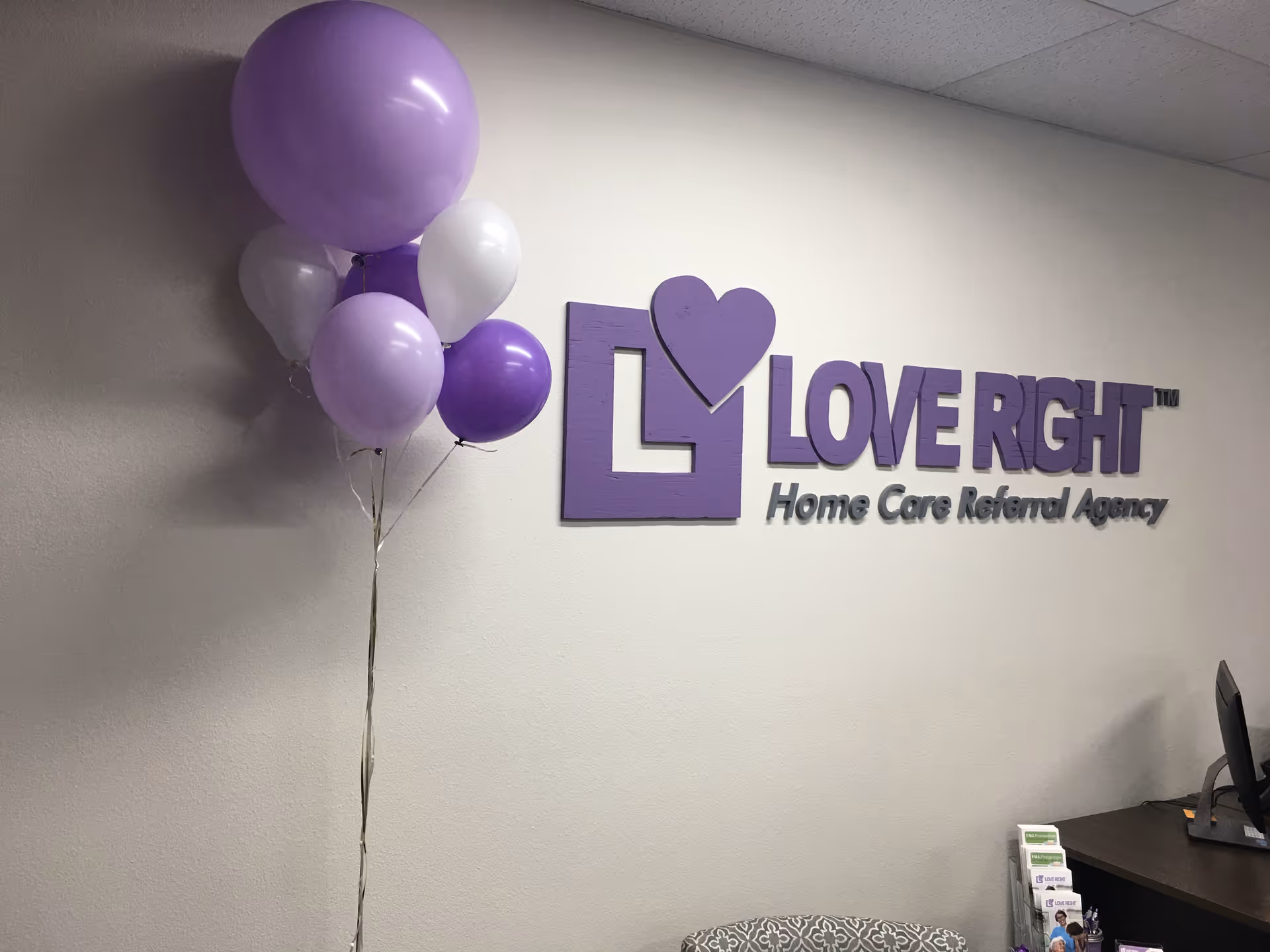 Reception area with purple balloons and a Love Right Home Care sign on the wall.