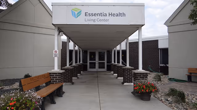 Exterior entrance of Essentia Health Living Center with a covered walkway, benches, and planters.