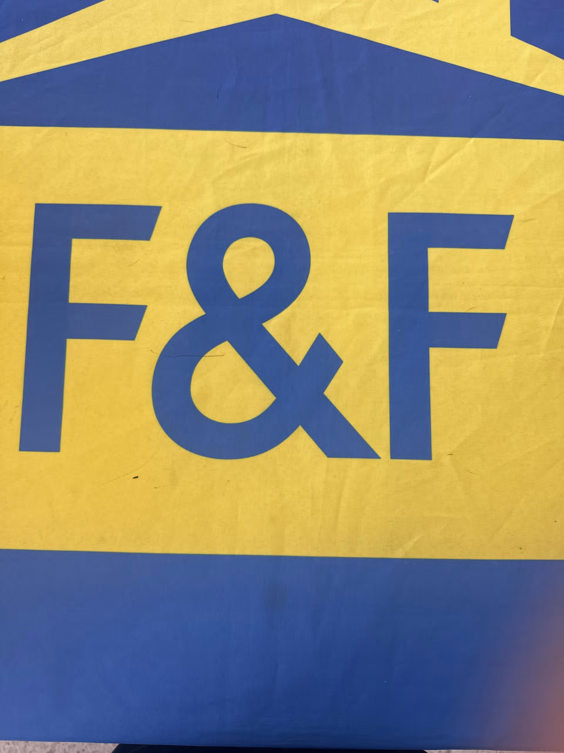 Close-up of a blue and yellow 'F&F' sign for Friends & Family Home Care.