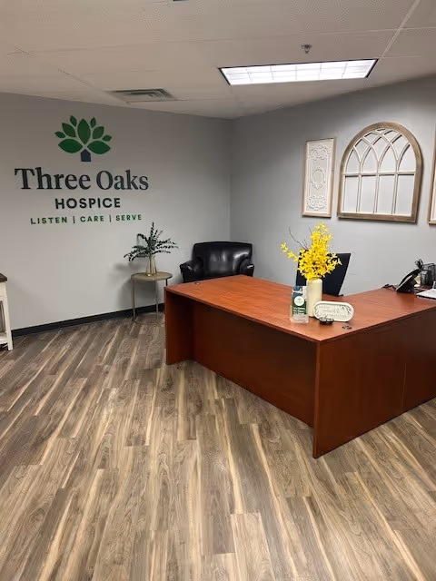 Reception desk in a hospice lobby with Three Oaks signage and decorative wall accents.
