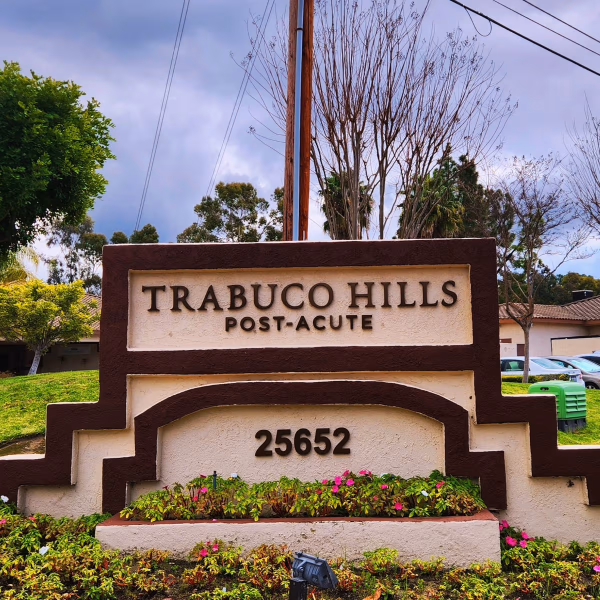 Stone sign reading Trabuco Hills Post-Acute with flowers in front