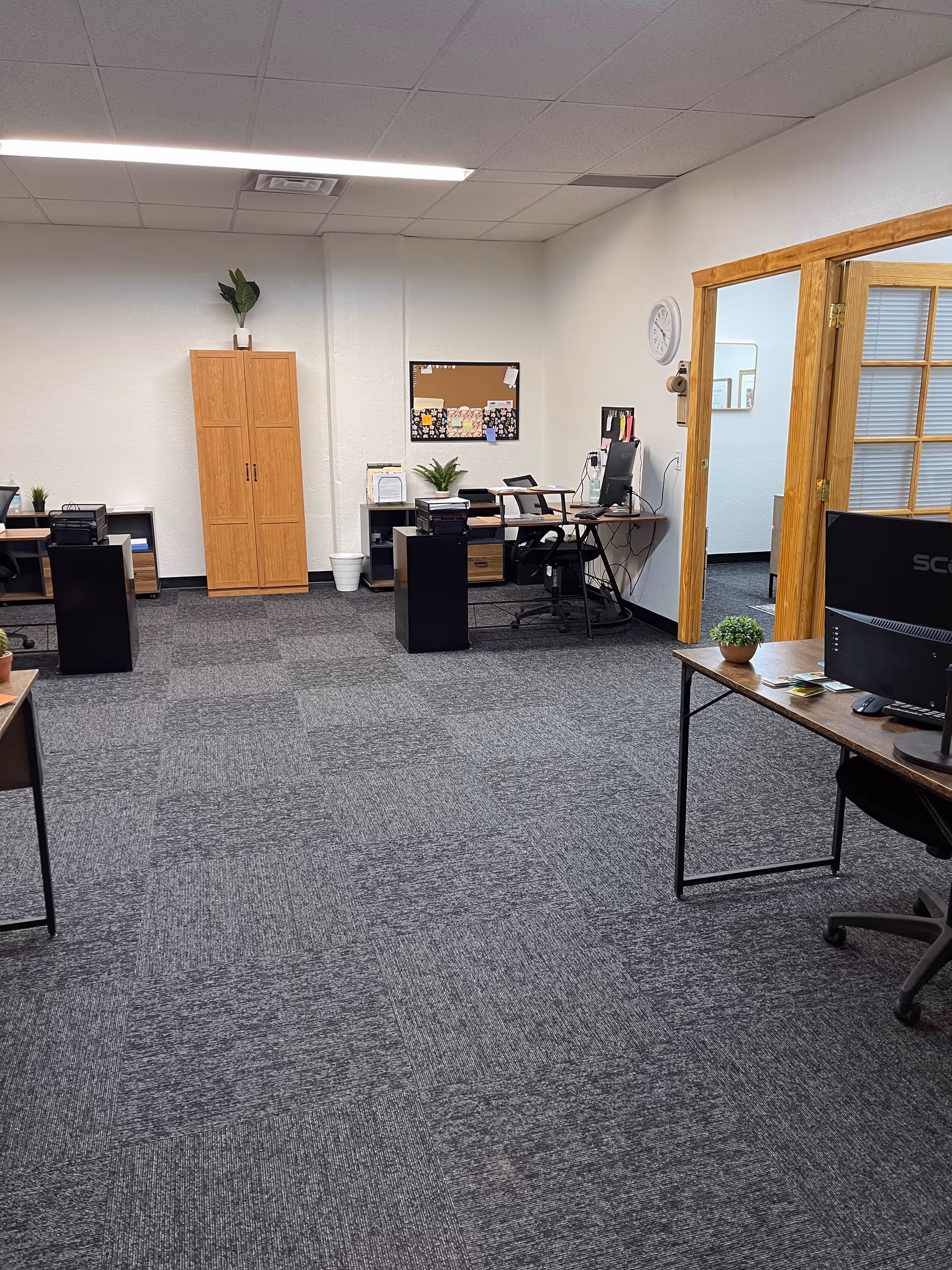 Office-like therapy academy interior with desks, computers, filing cabinets, and a glass doorway.