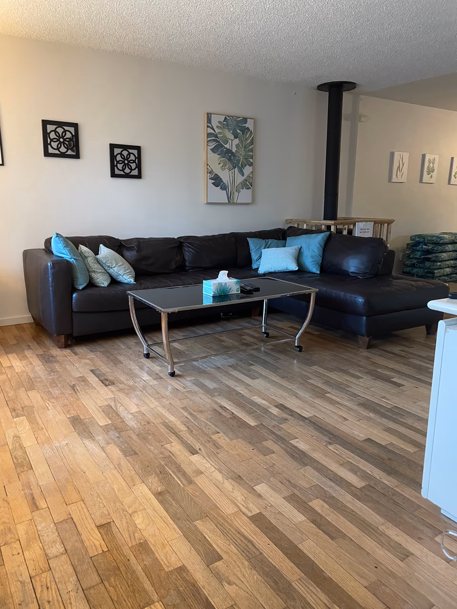 Cozy senior living lounge with sectional sofa, coffee table, wall art, and wooden floor.
