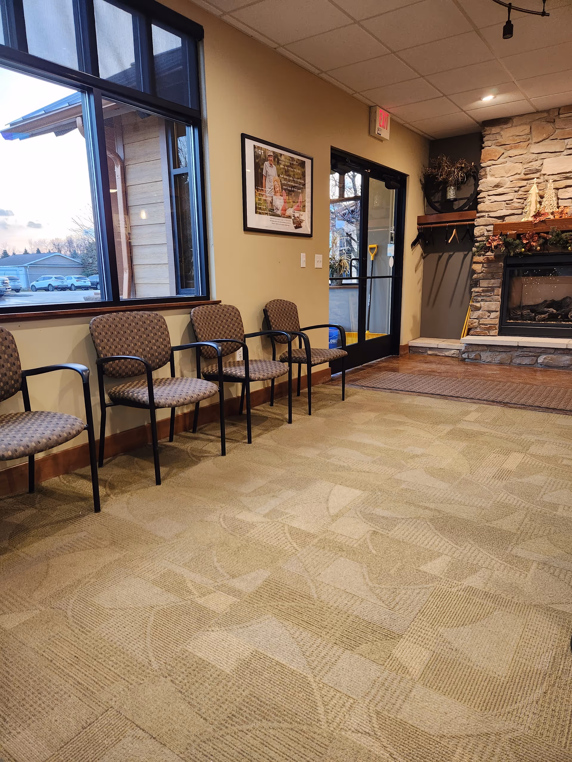 Waiting area with several chairs along a wall and a stone fireplace.