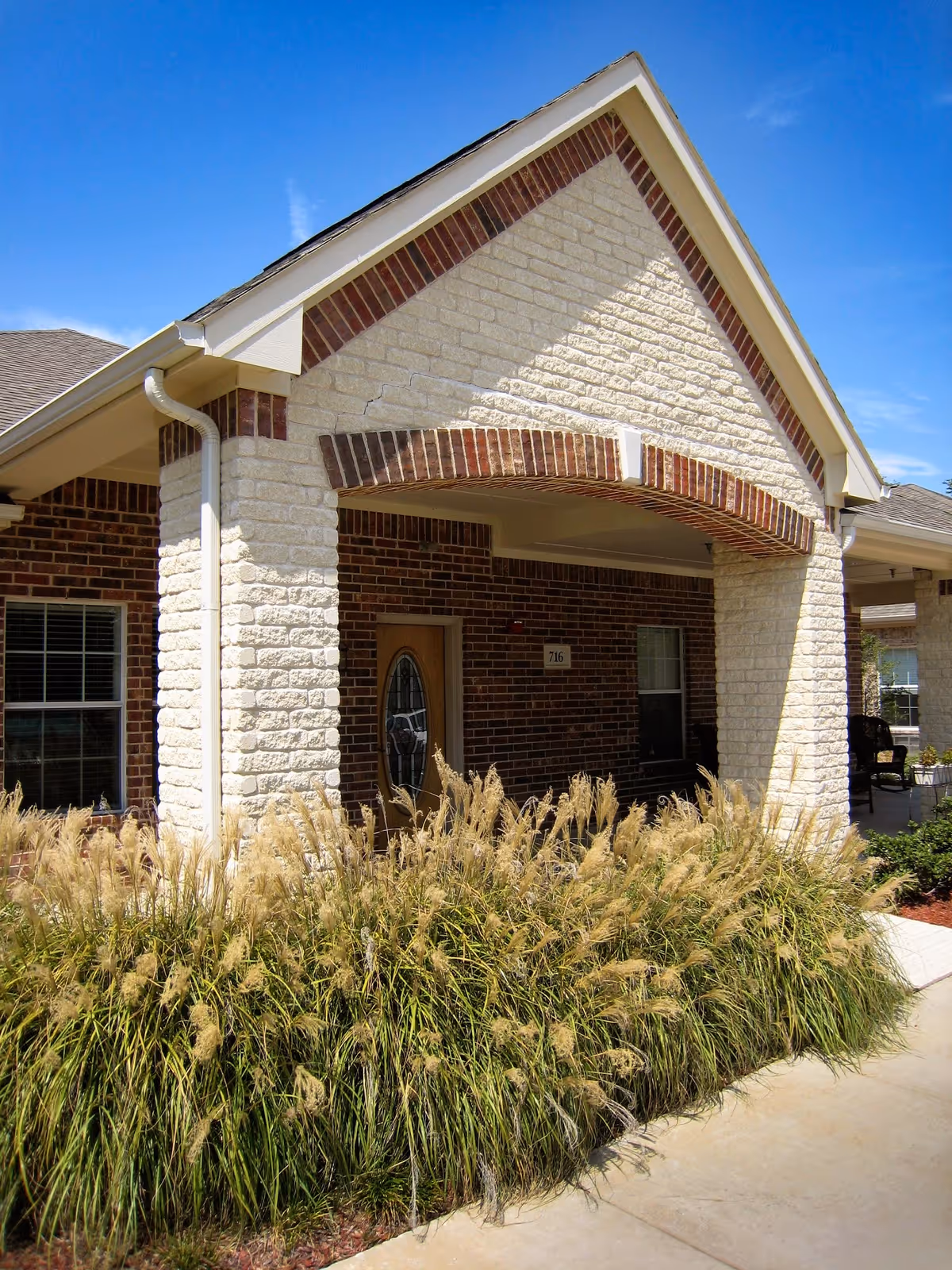Front exterior of Mustang Creek Estates Allen building with brick, stone, and grasses.