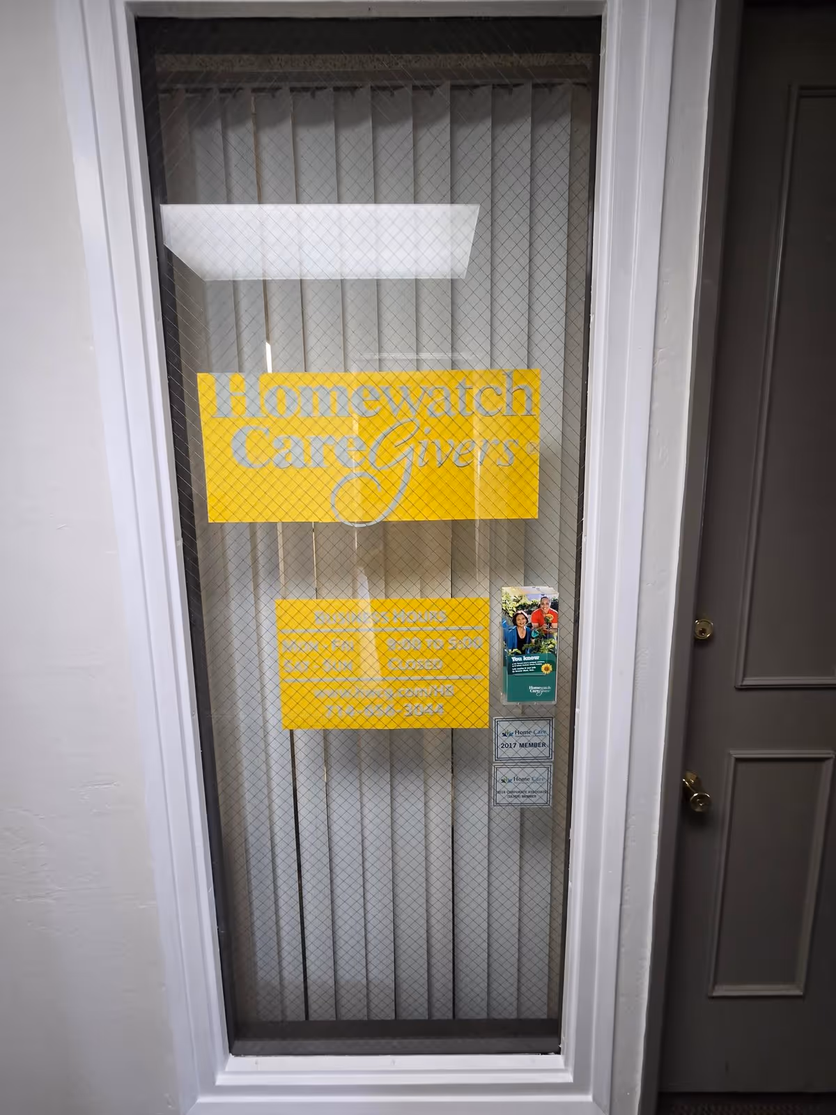 Front door with mesh screen and yellow Homewatch CareGivers sign