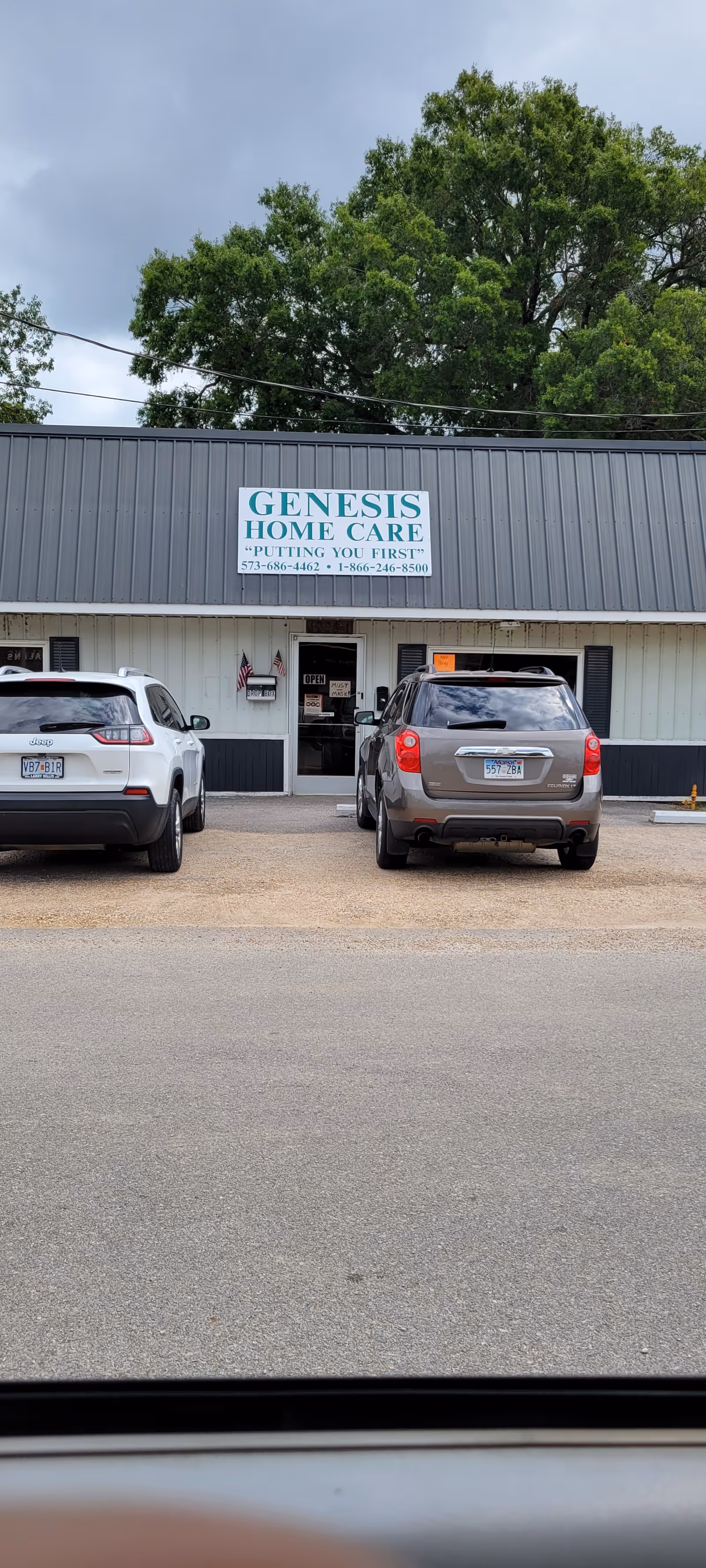 Front view of Genesis Home Care facility with two parked cars in the lot.