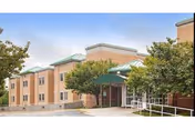 Exterior view of Lofland Park Center, brick building with green awnings, entrance, and trees.