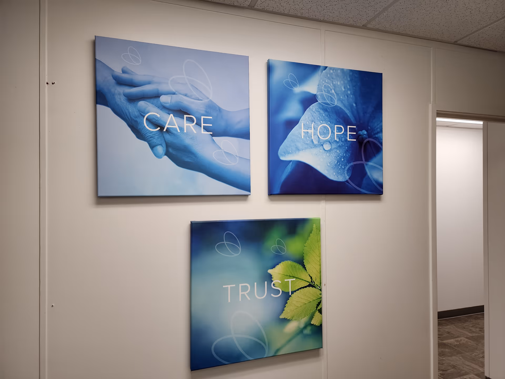 Wall hallway with three square art panels labeled CARE, HOPE, and TRUST.