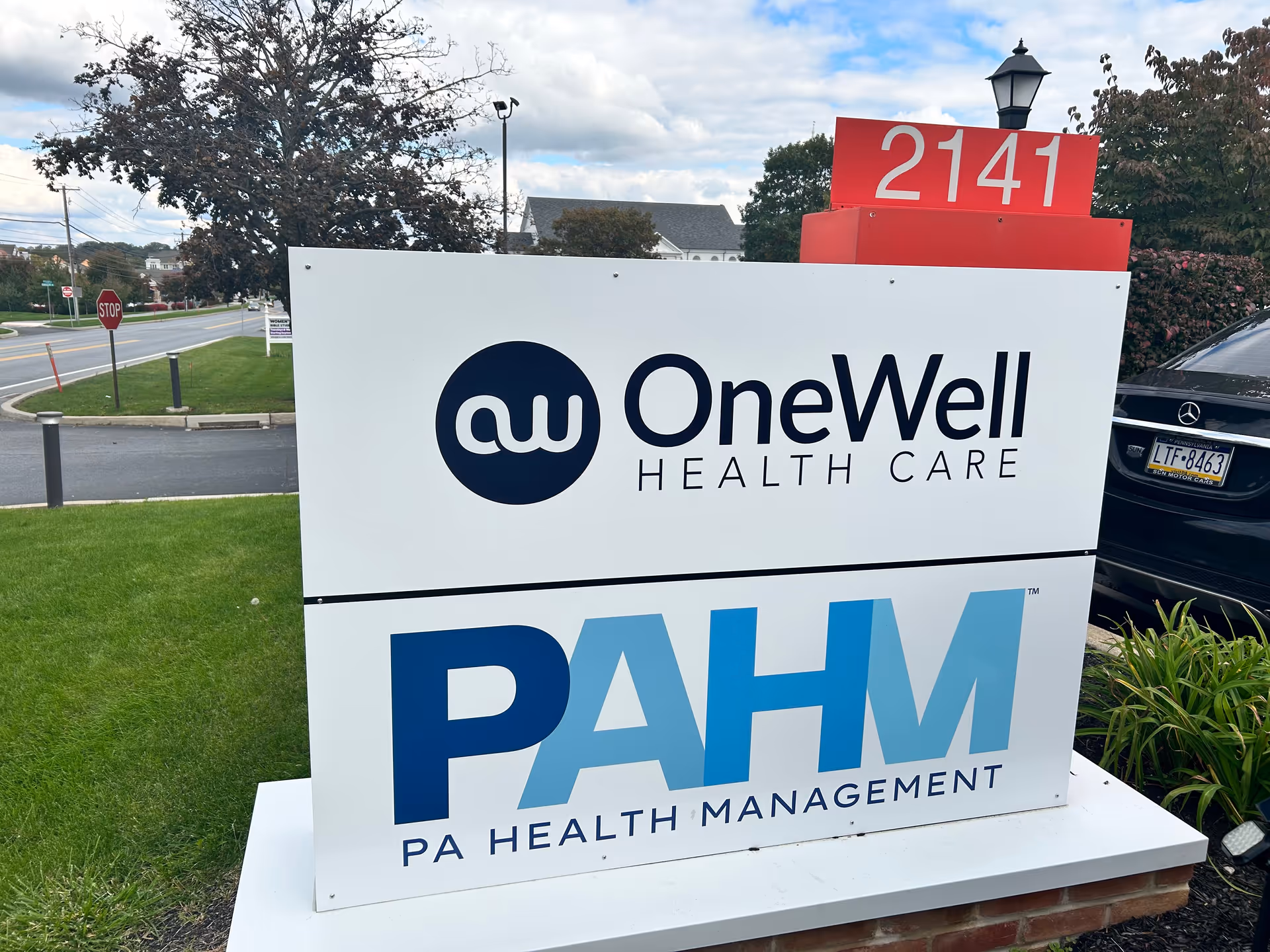 Large outdoor sign for OneWell Health Care and PA Health Management on a grassy lawn.