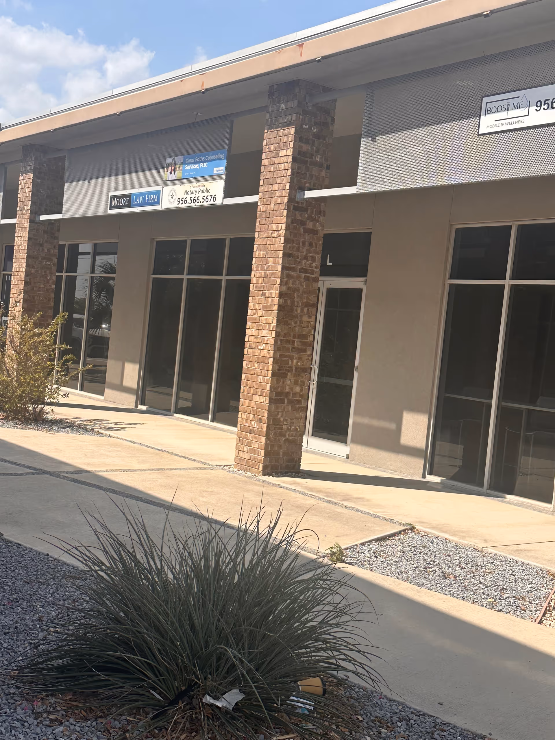 Exterior storefront with glass doors, brick columns, and business signs.
