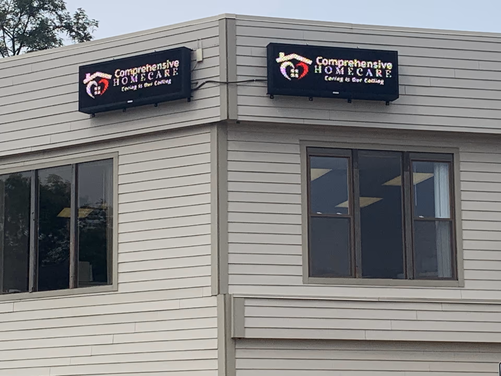 Exterior building frontage with two illuminated Comprehensive Home Care signs on the facade.