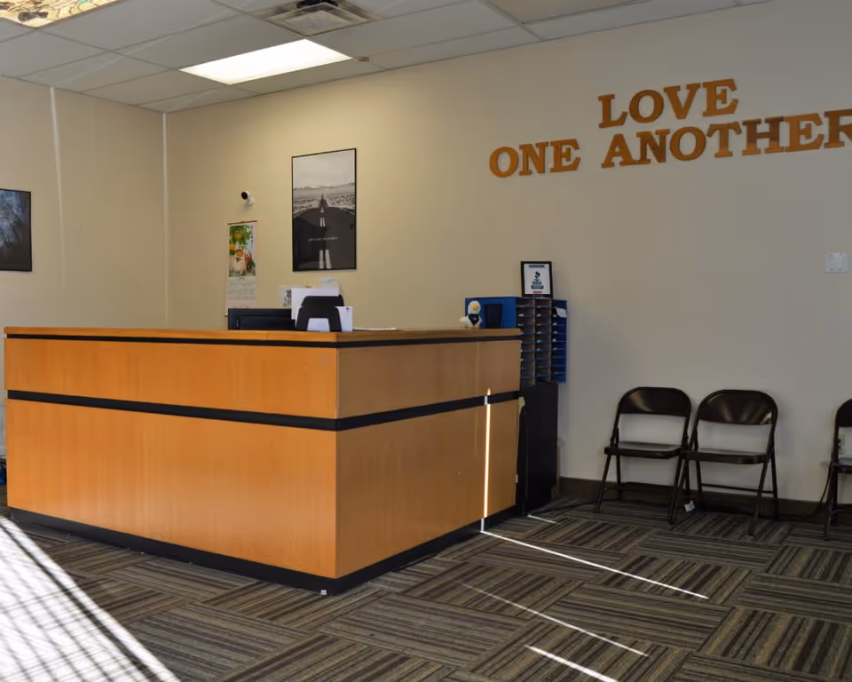 Reception desk in a facility lobby with chairs along the wall and a motivational sign.