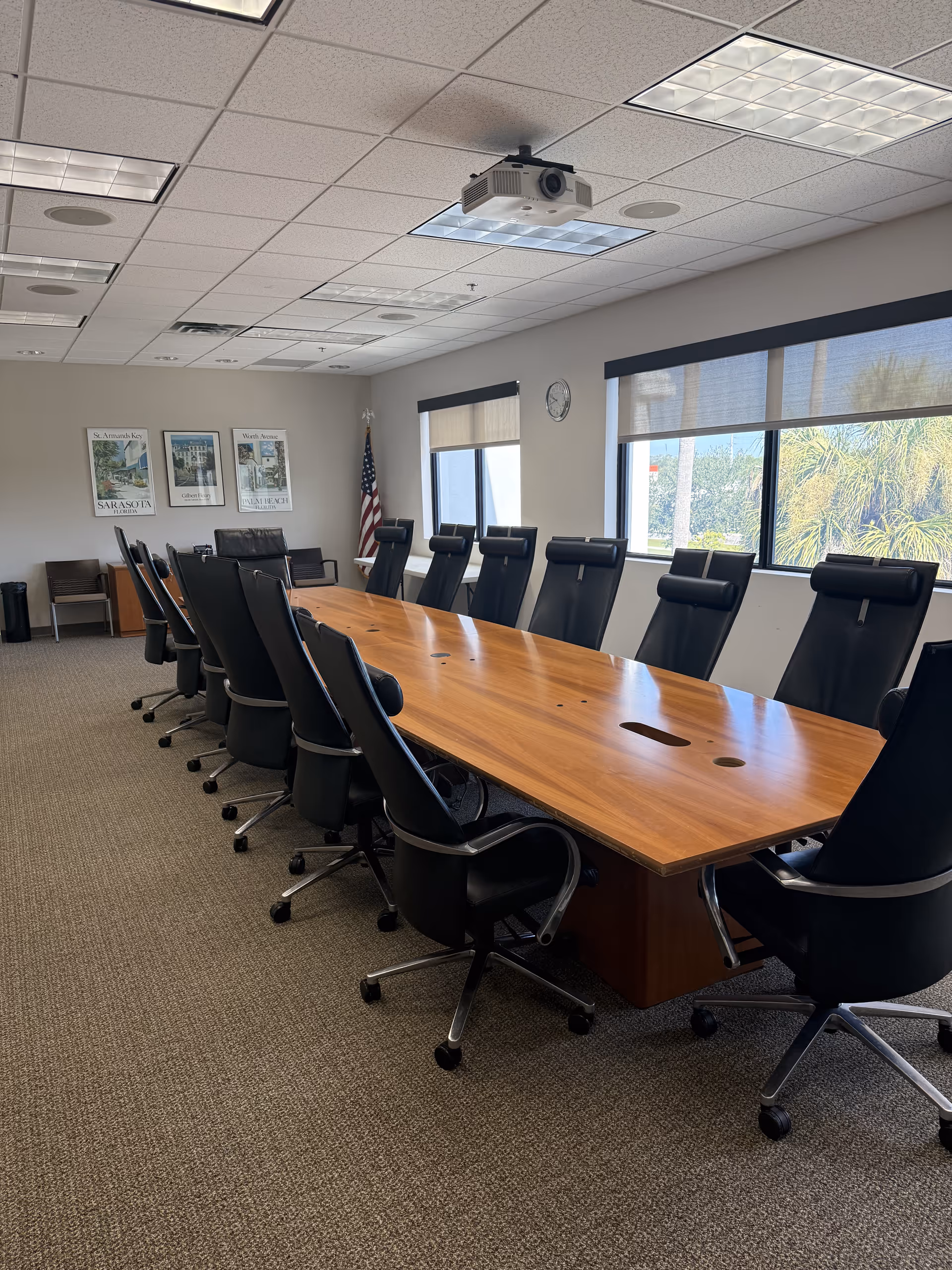 Conference room in a care facility with a long wooden table, black chairs, projector, and windows.