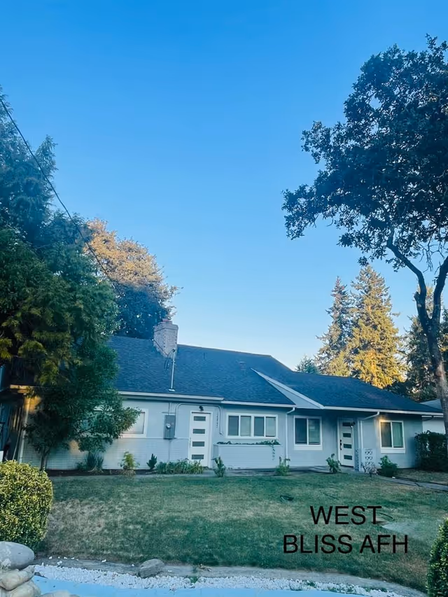Single-story light-blue facility building with front yard and trees, West Bliss AFH visible.