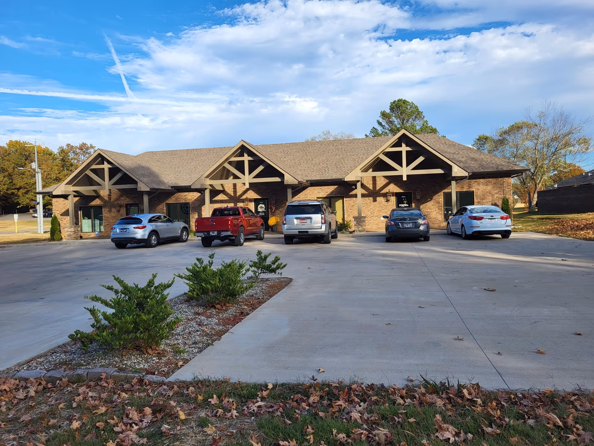 Brick building front of a senior care facility with multiple parked cars and a clear sky.