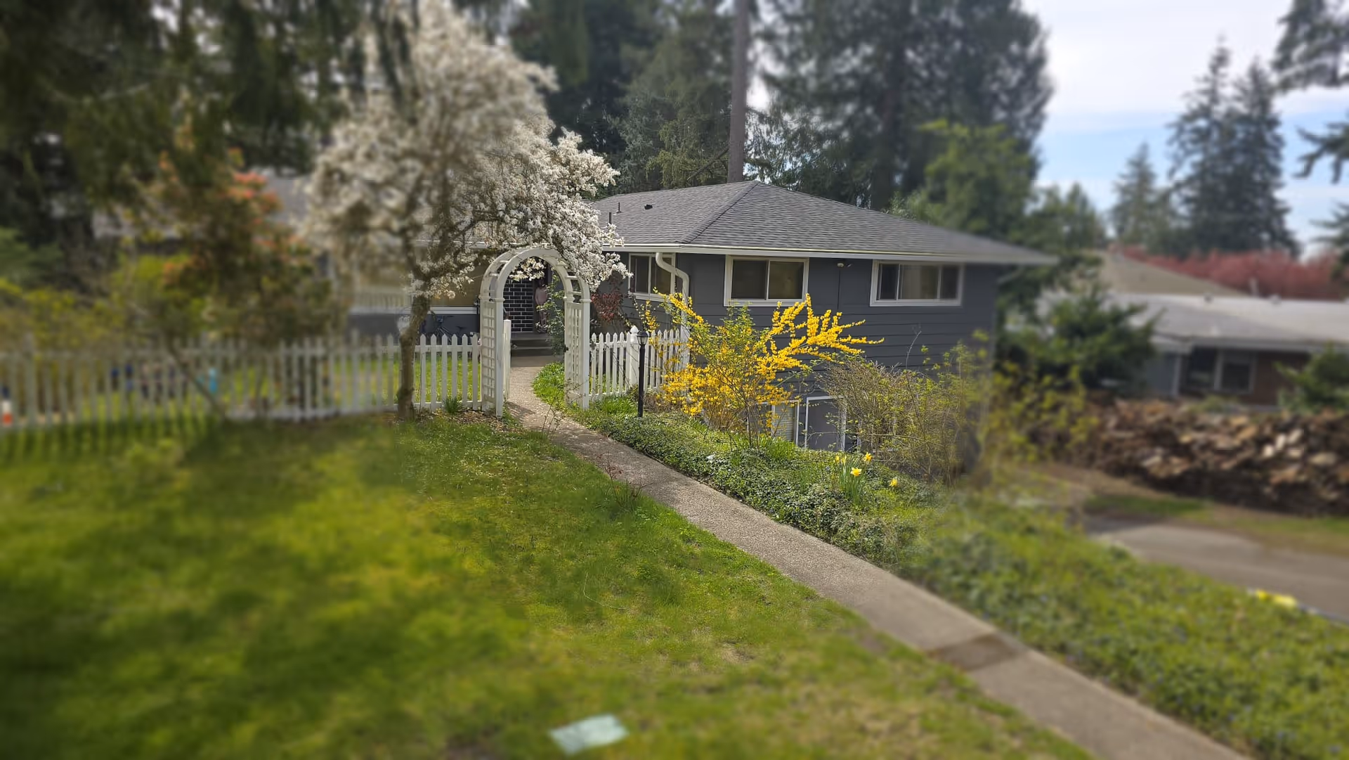 Exterior view of Trinity Haven Adult Family Home with a white gate, walkway, and landscaped yard.