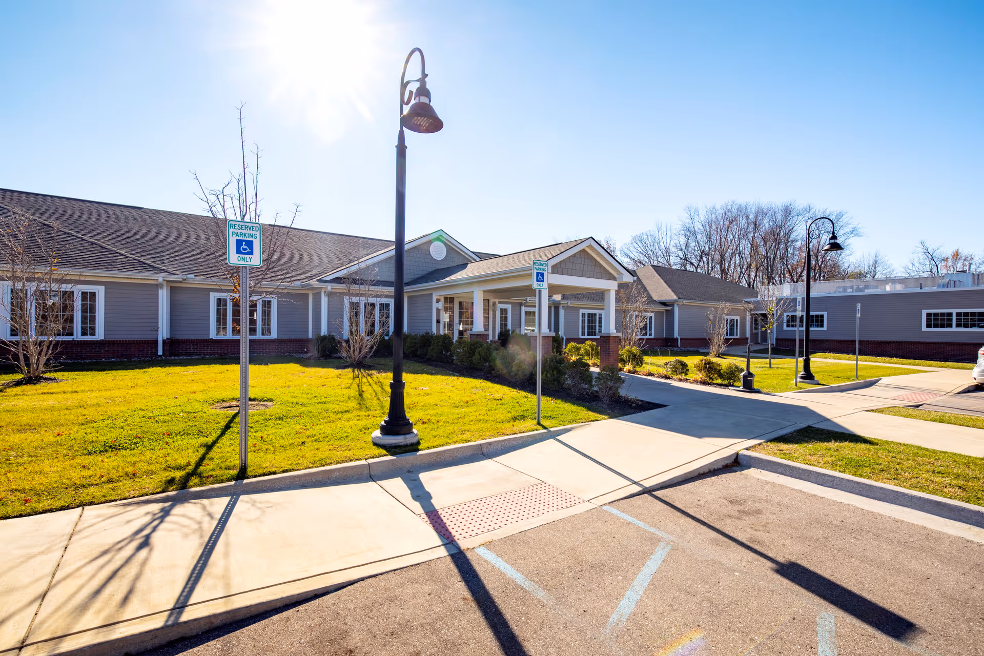 Single-story senior living facility exterior with a manicured lawn, sidewalk, and entry canopy.