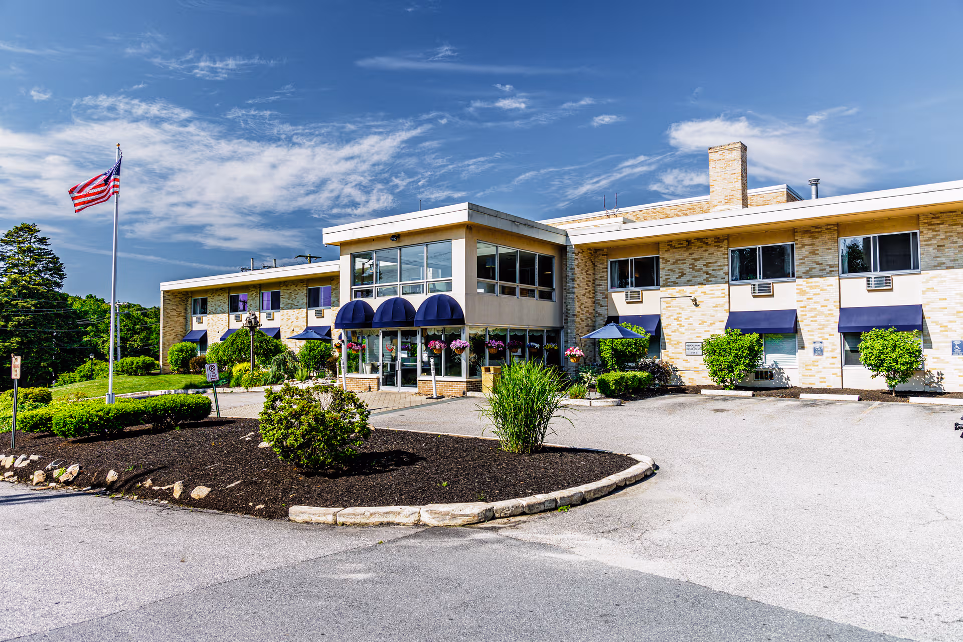 Front exterior of Briarcliffe Manor Skilled Nursing and Rehabilitation with a circular driveway and flag.