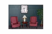 Two pink armchairs flank a small table with a lamp against a teal wall.