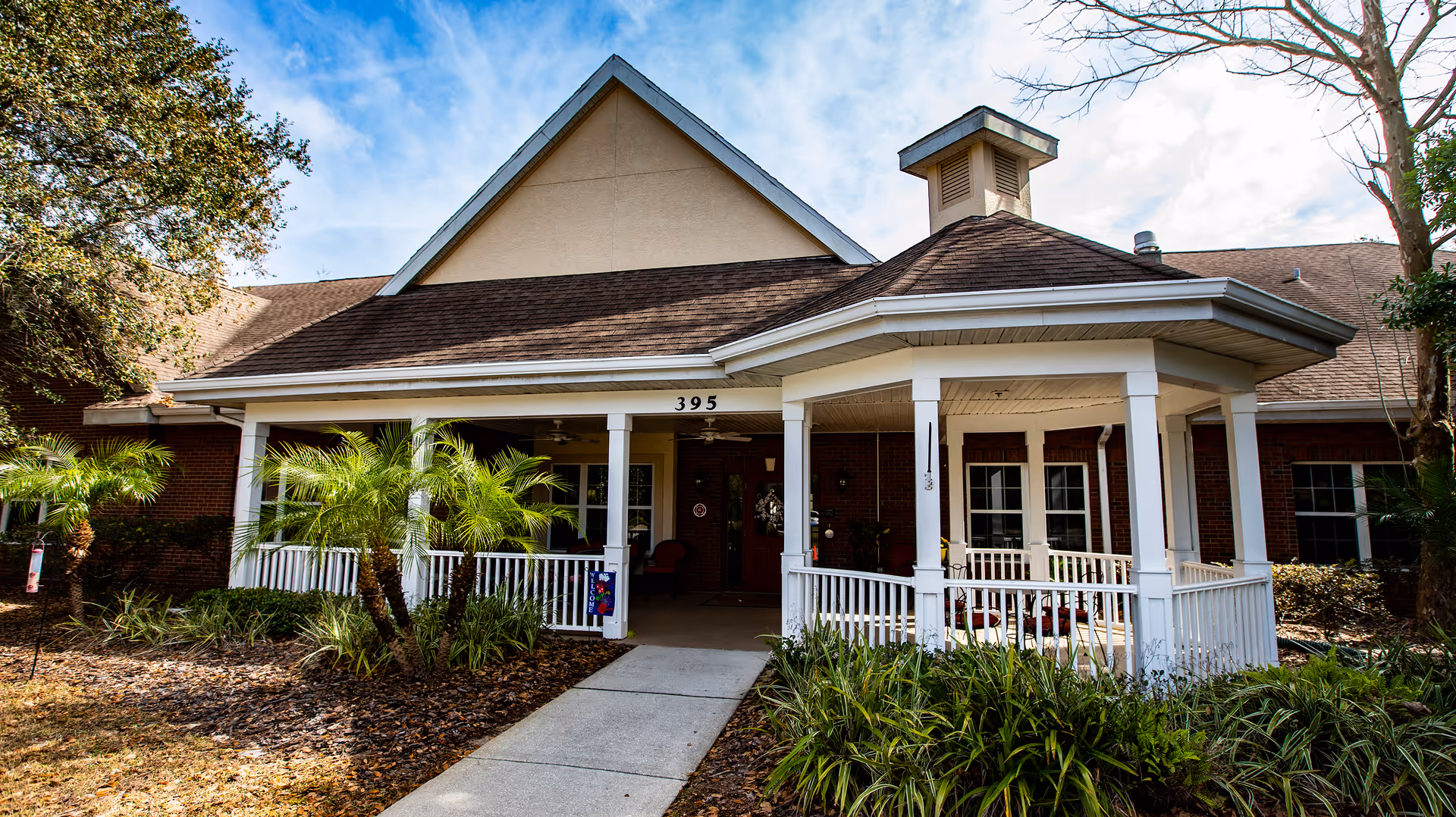 Front view of a senior living facility with a white wraparound porch and columns.