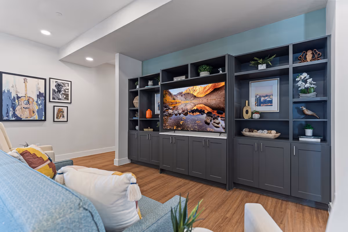 Modern living room with built-in gray entertainment center featuring a TV and decorative shelves.