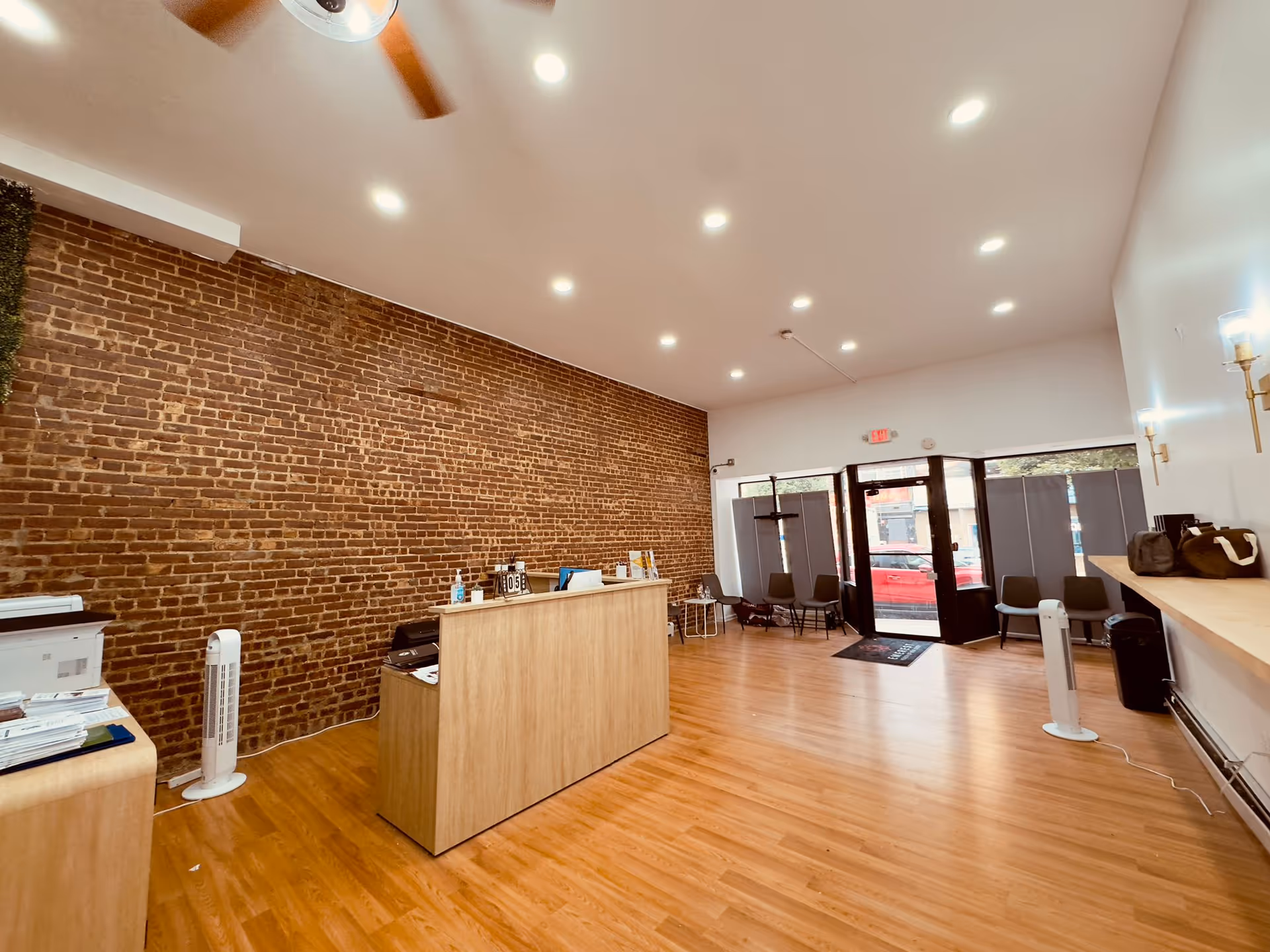 Lobby reception area with brick wall, wooden floor, and glass entrance doors.