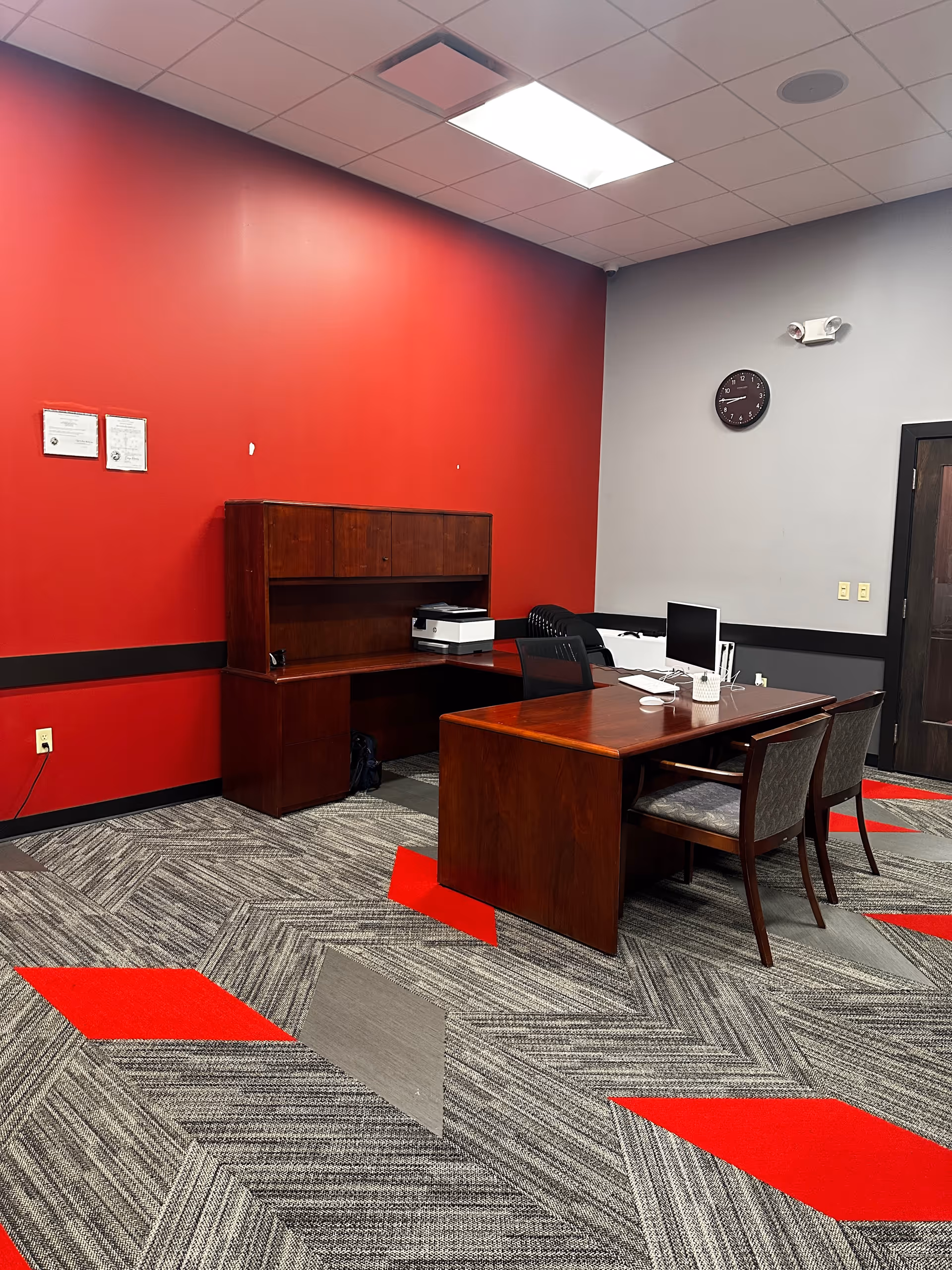 Administrative office in a senior care facility with a wooden desk and red walls.