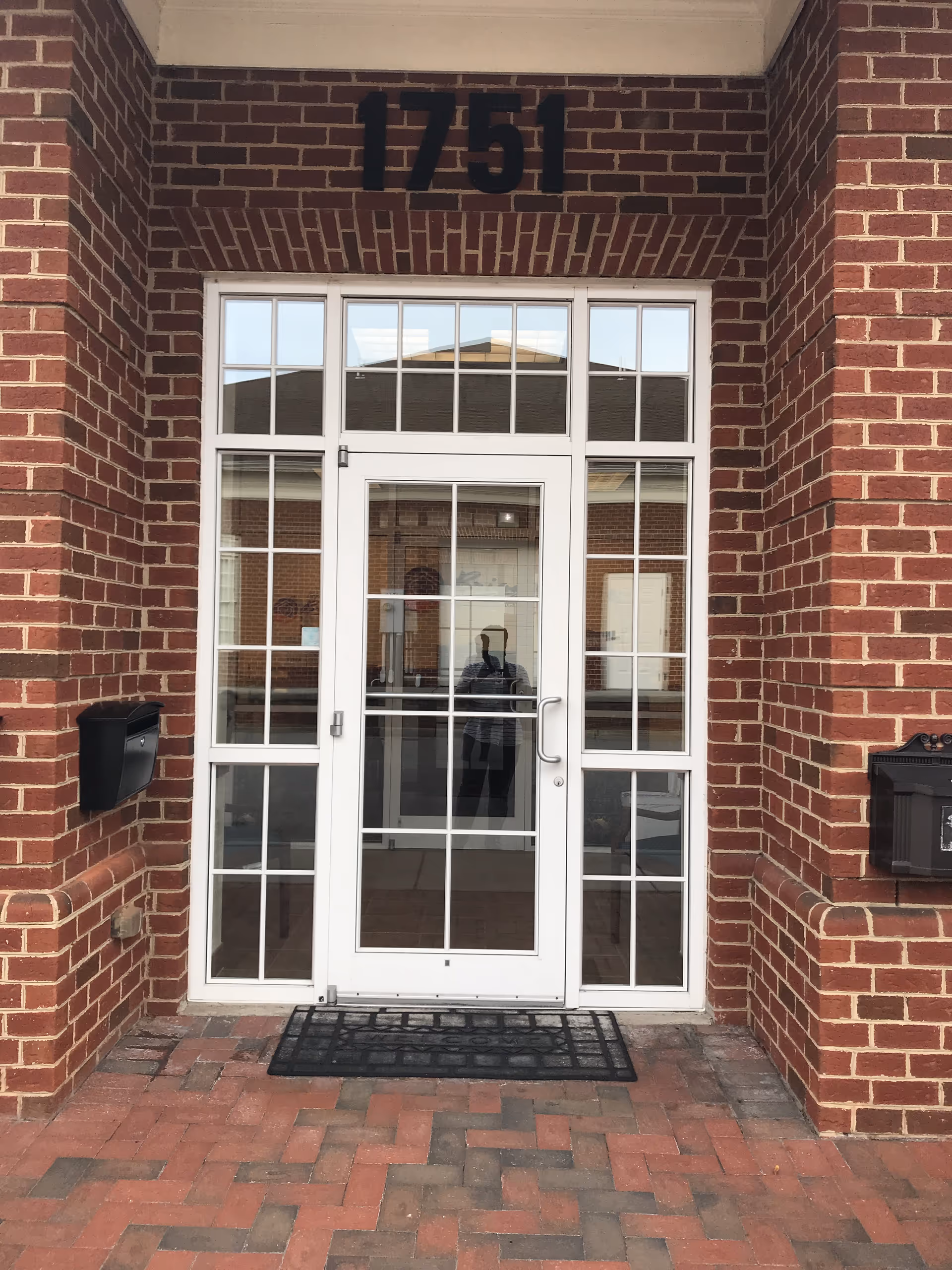 Brick building entrance with white glass door and 1751 above.