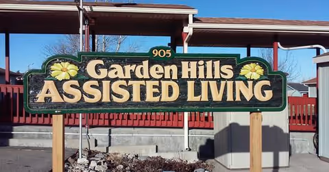 A large Garden Hills Assisted Living sign in a parking lot with a covered entrance.