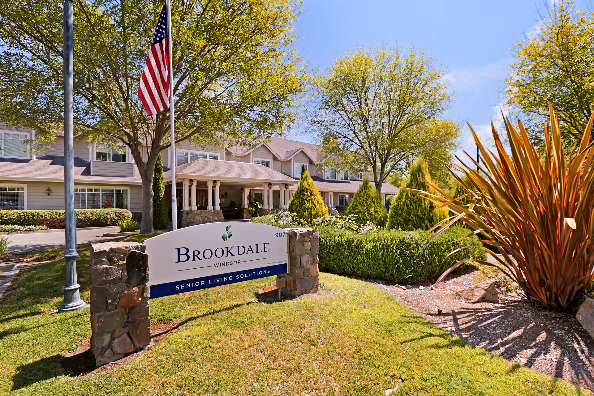 Brookdale Windsor exterior with sign, flagpole, and manicured landscaping.