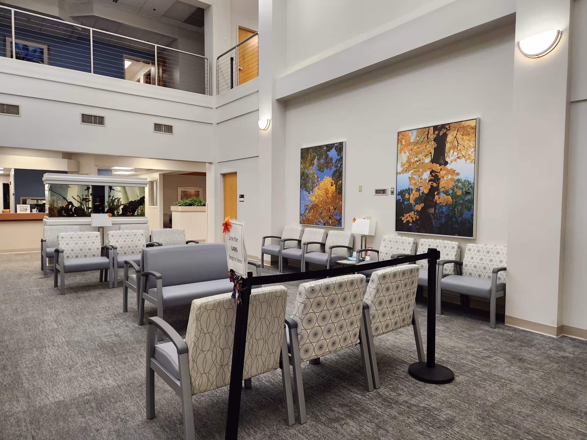 A spacious indoor lobby with grey seating, art on walls, and a front desk area.