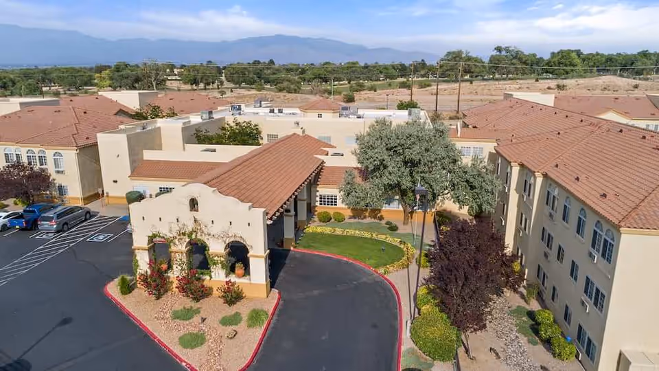 Aerial view of Morada Albuquerque senior living campus with beige buildings and red-tiled roofs.