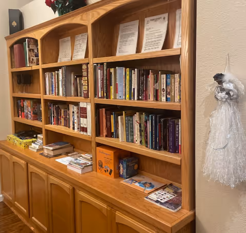 Wooden built-in bookshelf with books, papers, and small boxes along a hallway interior.