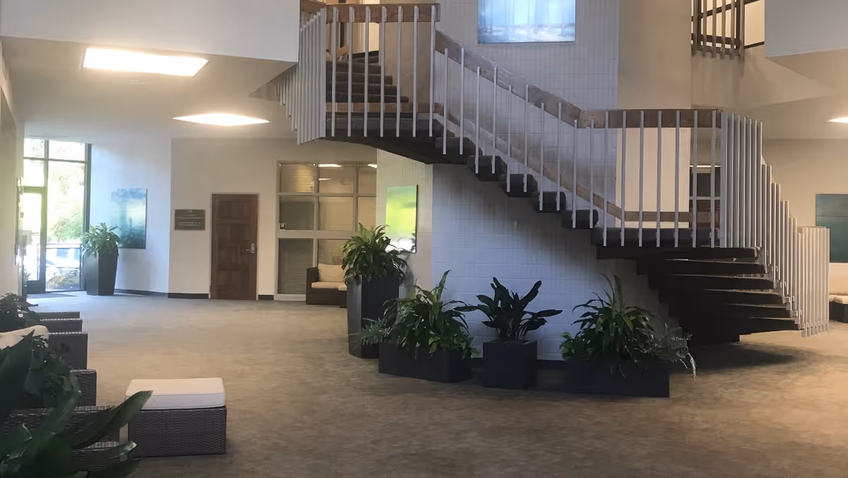 Spacious, well-lit lobby featuring a central spiral staircase and large potted plants.