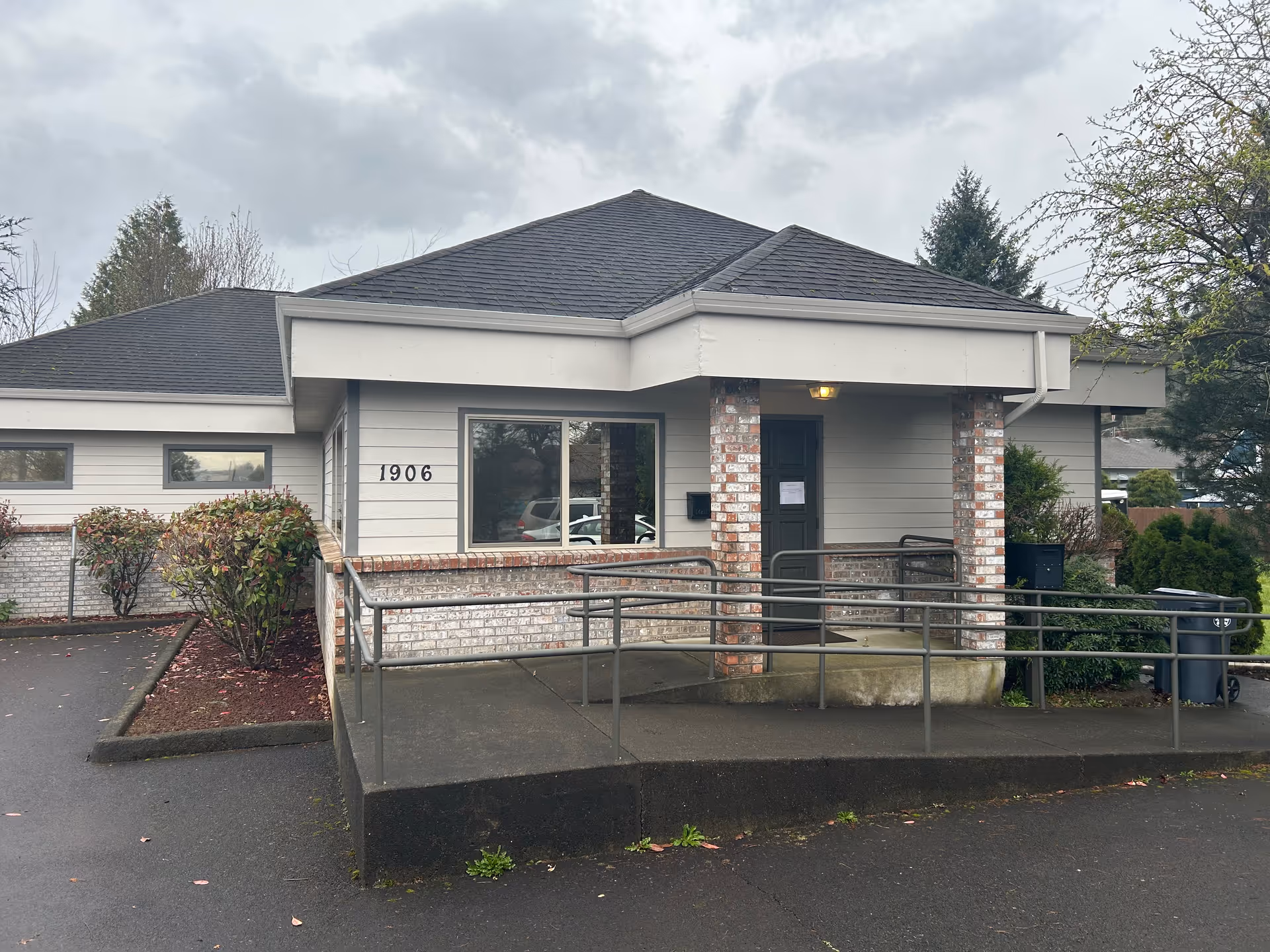 A single-story building with a ramp-access entrance, brick columns, and a paved driveway.