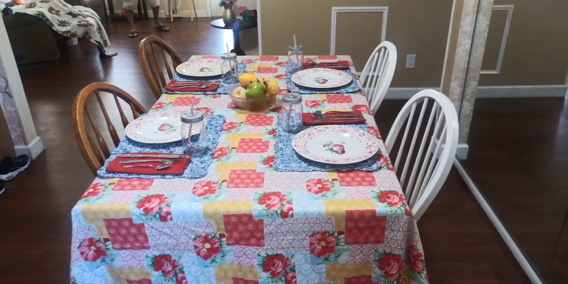 Colorful table set with plates and fruit in a dining room of a senior living facility.
