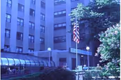 Exterior view of a multi-story senior living facility with glass entrance and American flag.