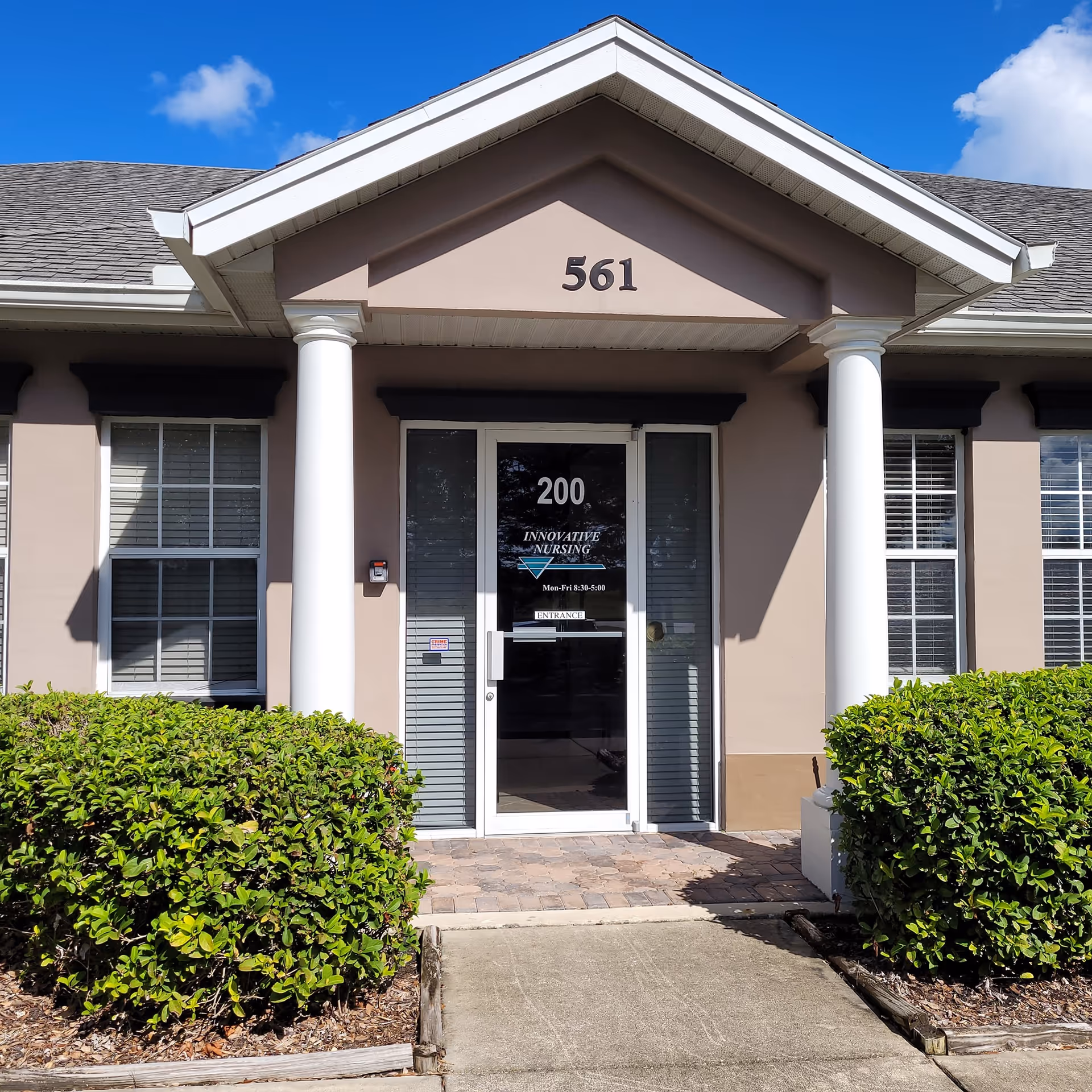 Exterior entrance of Innovative Nursing facility with double glass doors and columns.