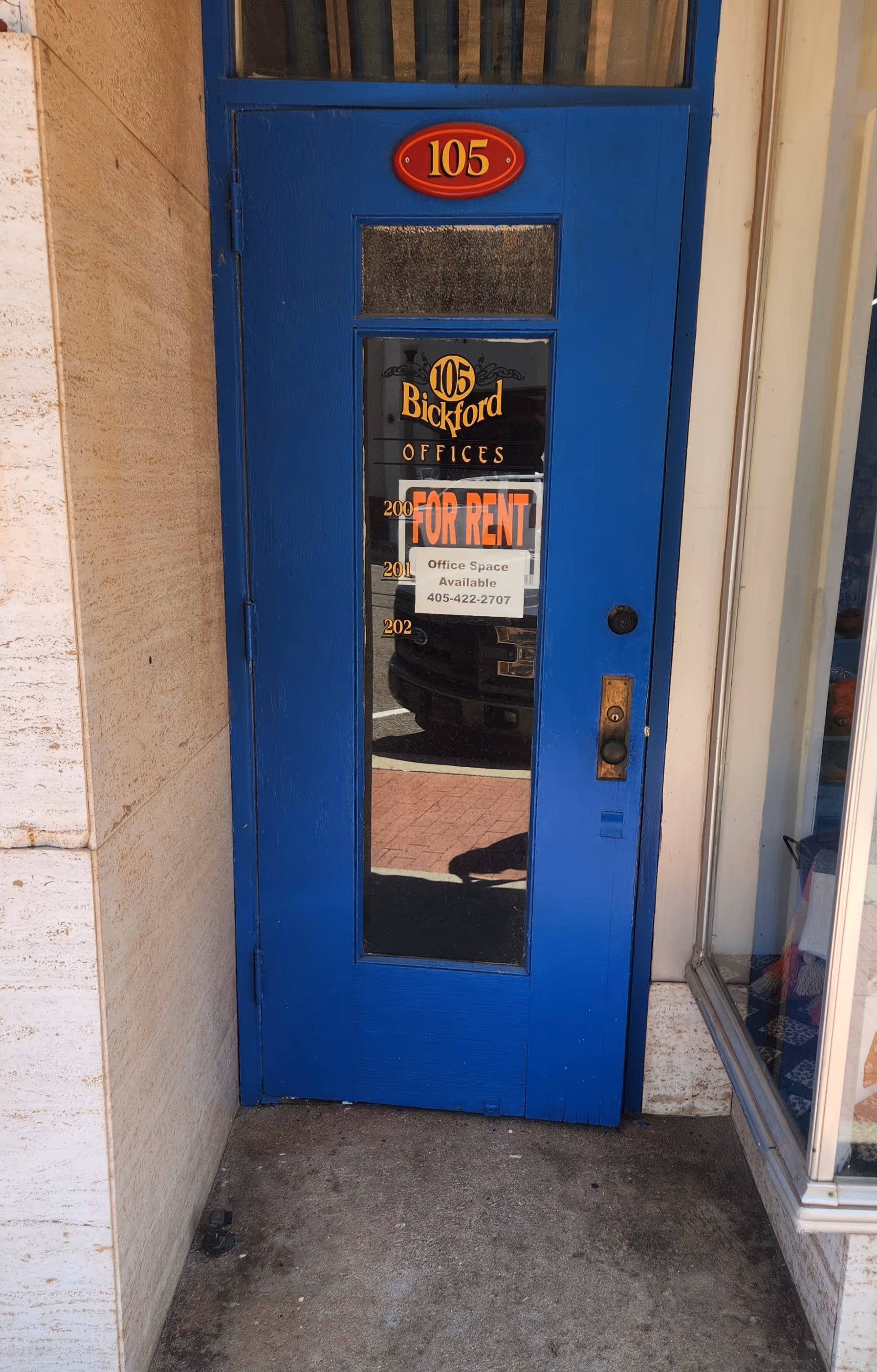 Bright blue exterior door with a 'FOR RENT' sign, set in stone walls.