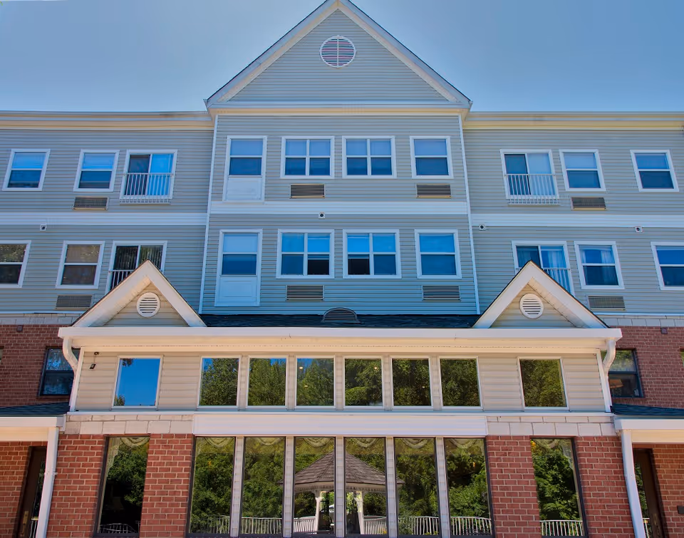 Exterior view of a multi-story senior living building with large windows and brick base.