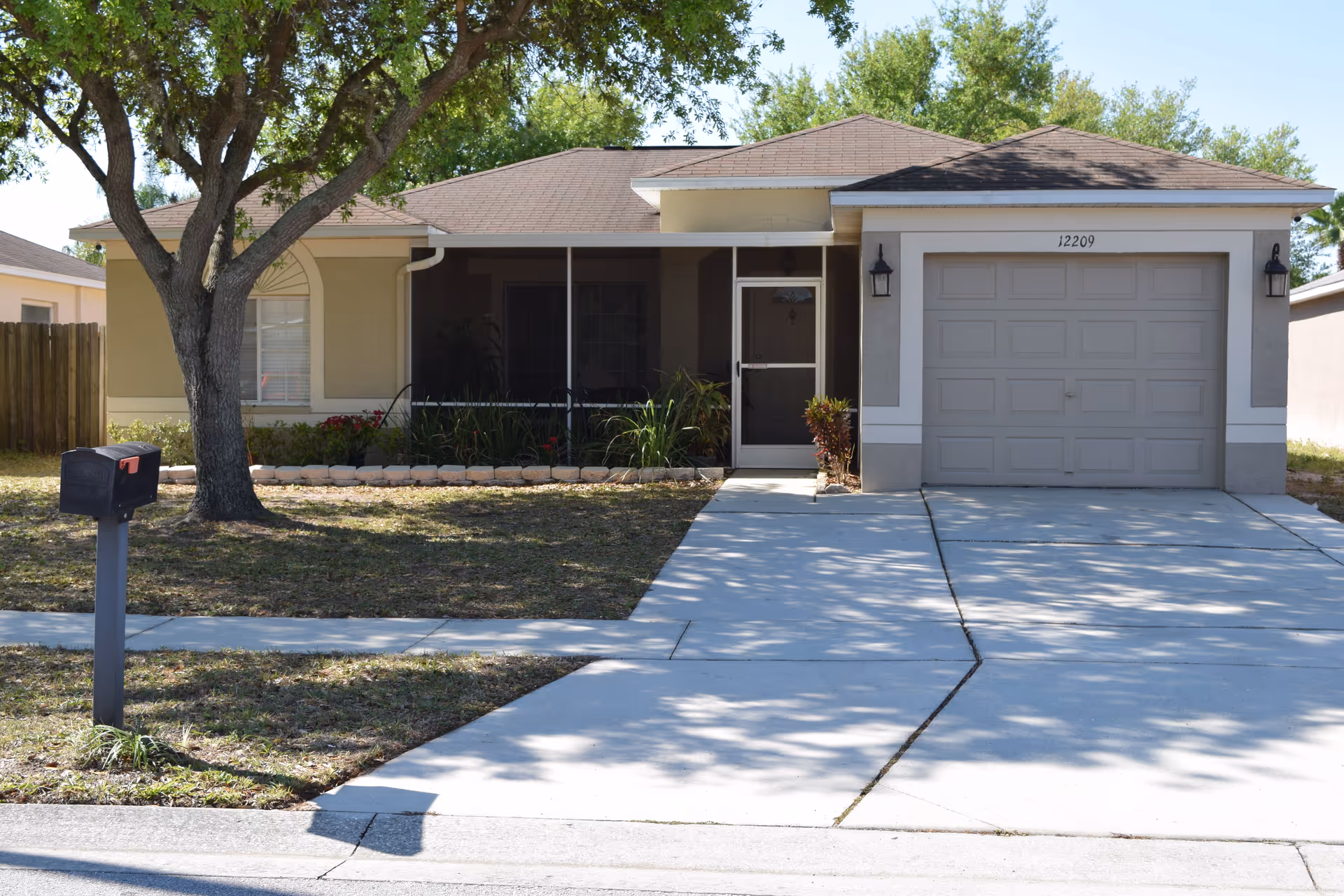 Front view of a single-story home-like facility with garage, driveway, and landscaped front yard.