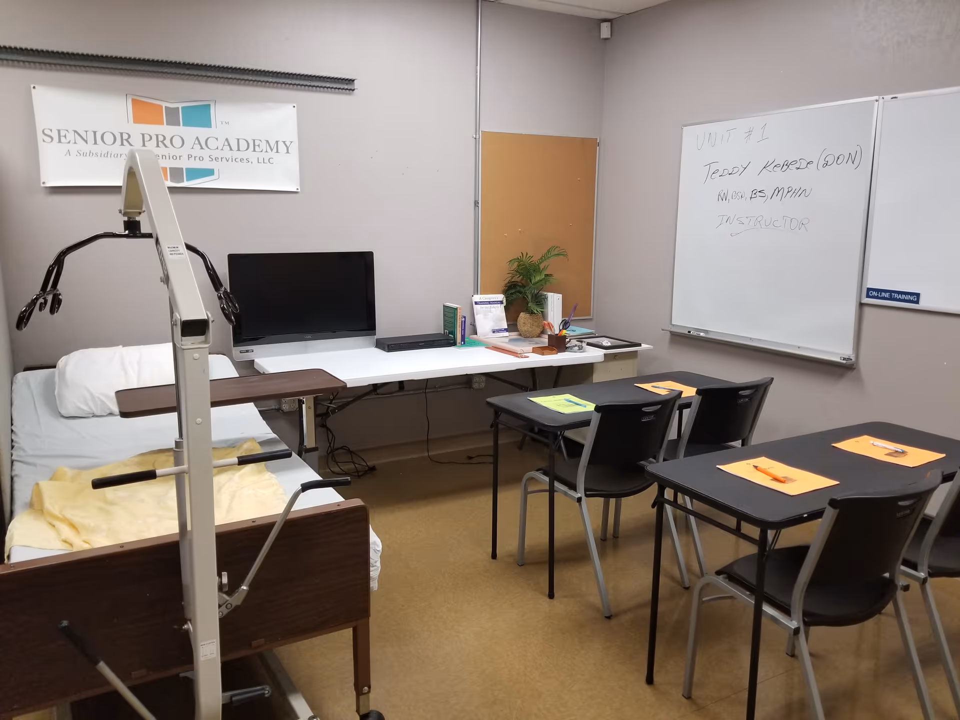 Training room inside Senior Pro Services with a bed, desks, whiteboard, and medical equipment.