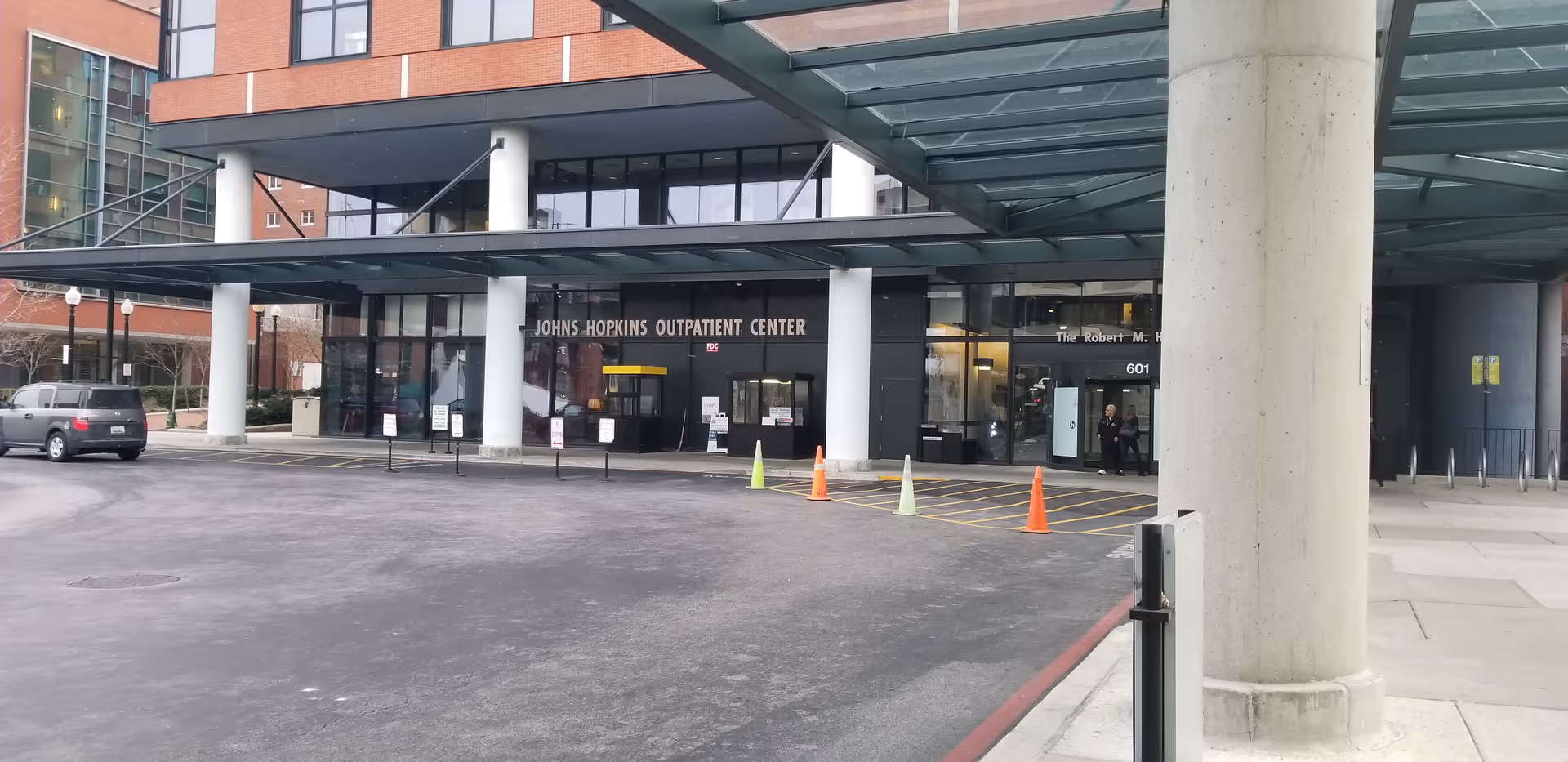Exterior view of Johns Hopkins Outpatient Center entrance with glass doors and cones.