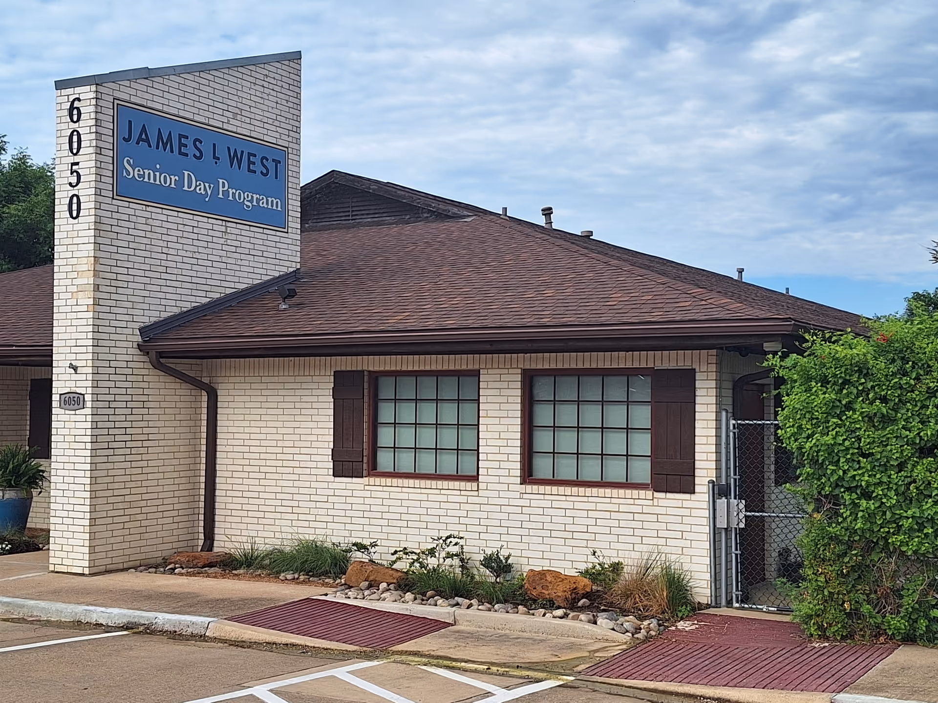 Exterior view of James L West Senior Day Program building with blue sign.