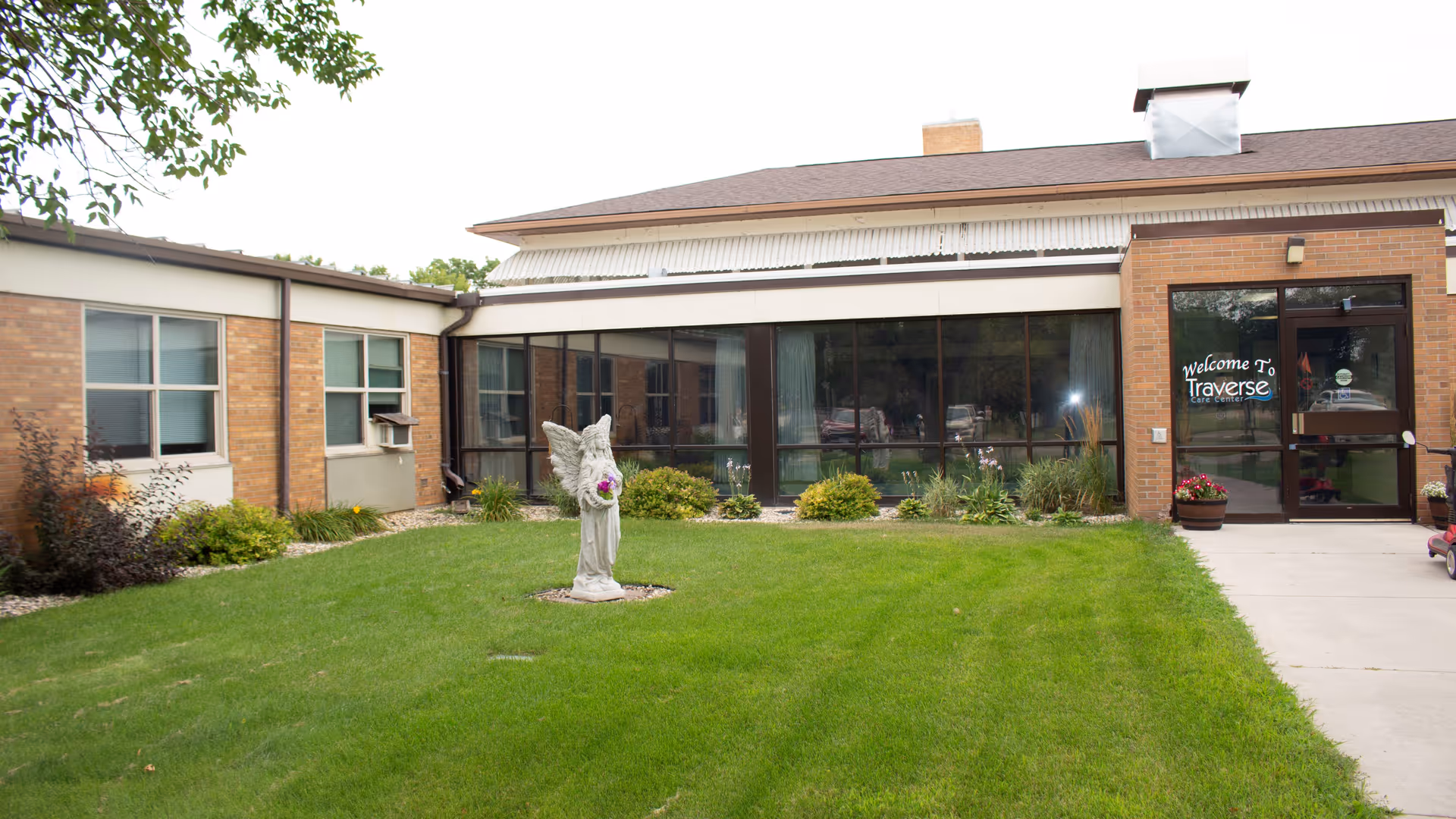 Exterior view of Traverse Care Center entrance with lawn, statue, and large glass windows.
