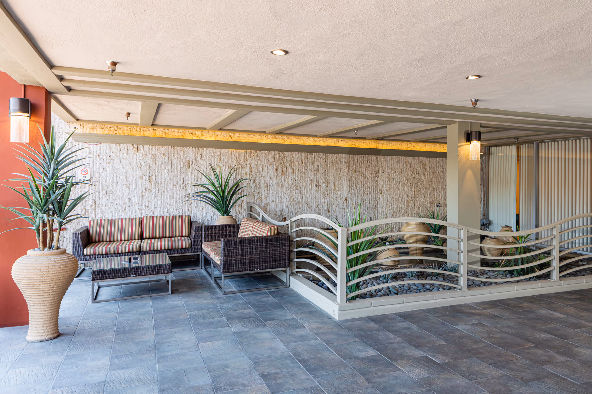 Outdoor seating area with wicker furniture, potted plants, and decorative railing.