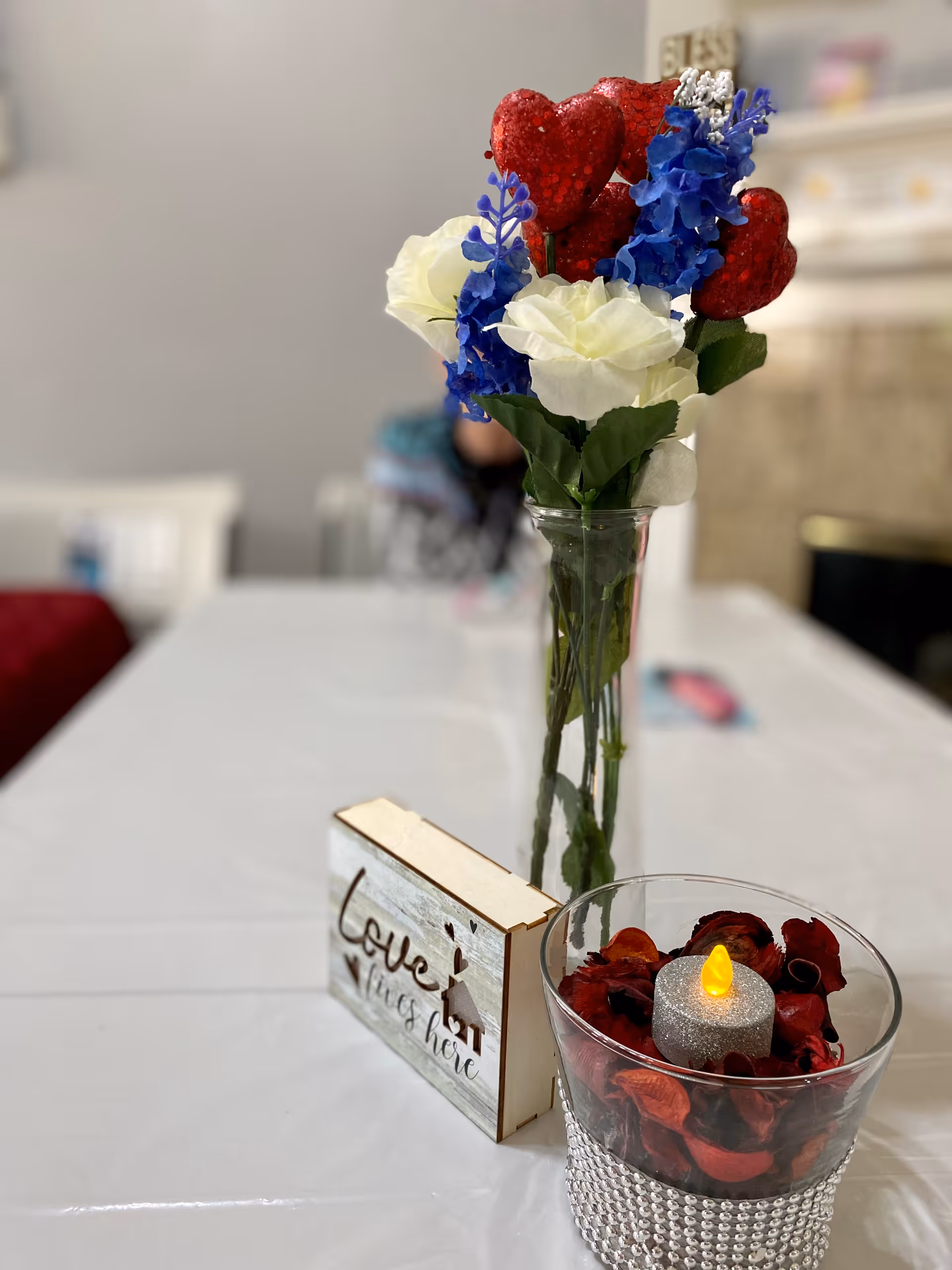 Vase of colorful flowers and a lit candle on a table in a senior living area.