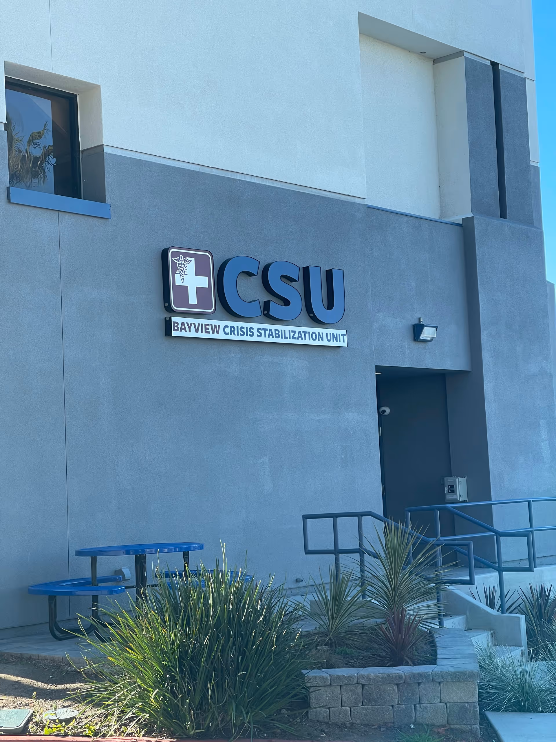 Exterior view of a building with CSU sign and blue outdoor seating.
